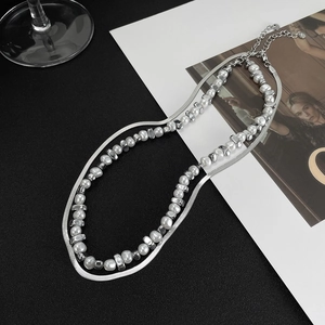 Detail view of double-layer necklace with irregular pearls and silver snake chain on card