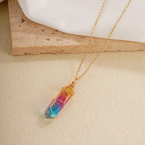 Rainbow hexagonal crystal pillar necklace with golden wire wrap on a beige stone base