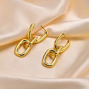 Three-link gold chain earrings with polished 18k finish on elegant silk background