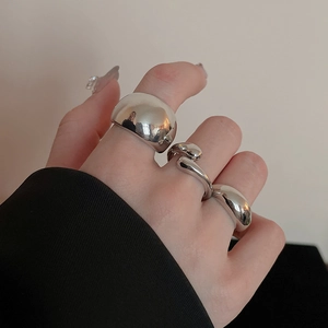Close-up of irregular silver bean rings set on model fingers with metallic finish