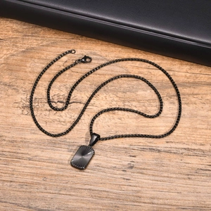 Macro detail of black stainless steel square pendant with radial texture on leather