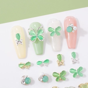 Detailed view of mint green cat-eye butterfly and bow alloy nail art charms with rhinestones
