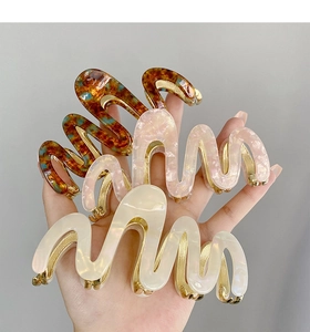 Detail of elegant wavy acetate hair claws with premium metal base and tortoiseshell patterns