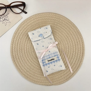 Detailed view of floral pattern fabric eyewear pouch on a rustic woven mat with glasses