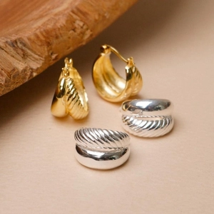 Macro detail of gold and silver croissant earrings with twisted and smooth metal textures