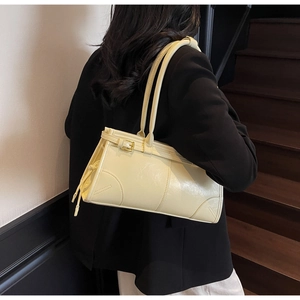 Detailed side view of yellow faux leather shoulder bag with metallic buckle and twin straps