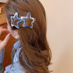 Detail showing star-shaped blue plaid hair clips worn on side hair for a casual look