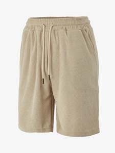 Detail of waffle textured fabric and drawstring waistband on beige men's casual shorts