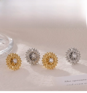 Close-up of gold and silver sunflower earrings with sparkling zircon stones