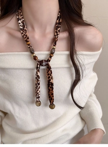 Detail of leopard print ribbon necklace with golden beads and star planet logo pendant