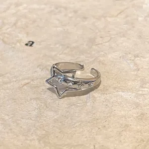 Close-up of adjustable silver star ring with embossed details on a neutral textured background