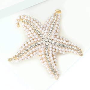 Macro shot of gold-plated starfish brooch with embedded pearls and sparkling crystals