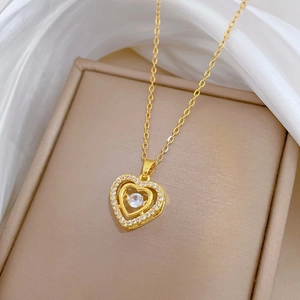 Macro shot of double heart pendant necklace with shimmering crystals on beige display pad