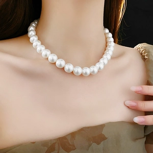 Gros plan d'un collier de grandes perles blanches rondes brillantes sur un mannequin
