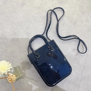 Detail of a navy blue jelly handbag with glossy PVC finish and detachable strap