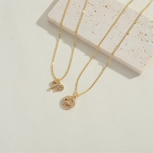 Elegant gold necklaces with crystal bow and angel coin pendants on light stone