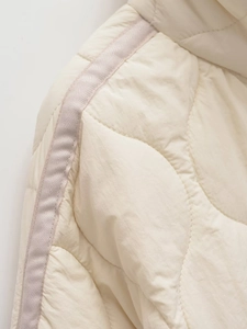Detail of cream quilted jacket showing nylon fabric texture and drawstring shoulder seam