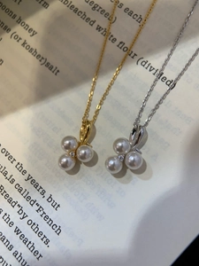 Detail view of pearl petal necklace in gold and silver over vintage book page