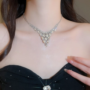 Macro detail of silver V-shaped tassel necklace with sparkling rhinestones on model