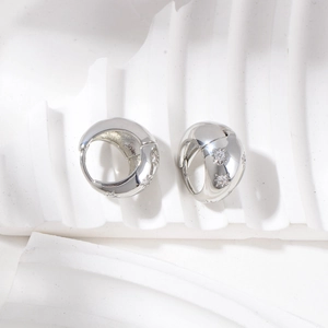 Detailed shot of silver hoop earrings with star relief and white zircon inlay