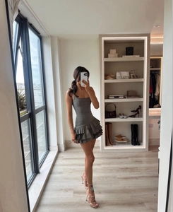 Detailed view of taupe sleeveless pleated mini dress with multi-layered ruffled hemline