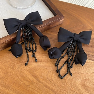 Close-up of black fabric bow earrings with crystal tassel beads and flower pendants