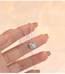 Close-up of a silver rose flower necklace pendant with a sparkling zircon inlay detail