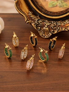 Detail of vintage hoop earrings with multicolored zircon stones on a dark wood surface