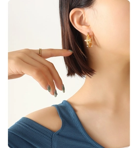 Détail d'une boucle d'oreille en U martelée avec perle et incrustation de zircon