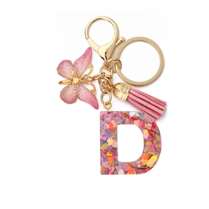 Detail of resin letter D keychain with heart sequins, pink butterfly and gold clasp