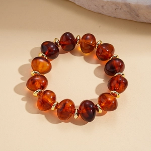 Detail of amber acrylic oval beads and golden metal spacers on a vintage style necklace