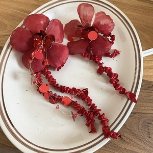 Detailed close-up of red fabric floral tassel earrings with sequins and long ribbons