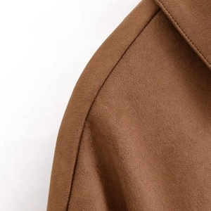 Detailed close-up of brown suede fabric texture and shoulder stitching on jacket