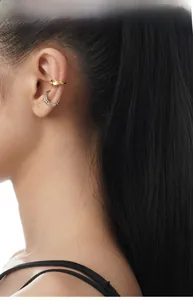 Detail of silver zirconia stud and gold leopard ear cuff on model's ear