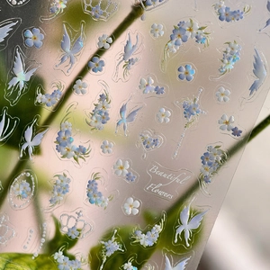 Pegatinas para uñas de flores y mariposas con acabado iridiscente sobre fondo verde