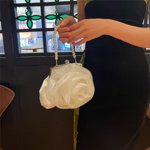 Close-up of a white 3D rose satin evening bag with a round pearl handle and metal clasp