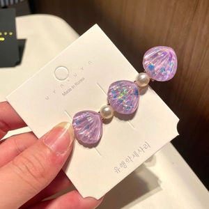 Detail of purple iridescent shell hair clip with white pearls on display card