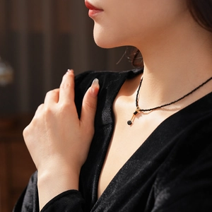 Close-up of vintage black crystal beaded necklace with gold geometric pendant on model neck