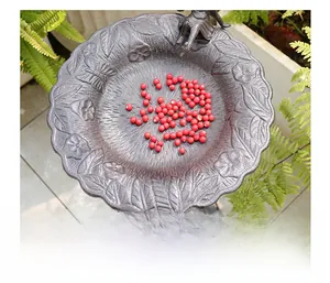 Detalle de comedero para pájaros de hierro fundido con flores y cuentas rojas decoradas