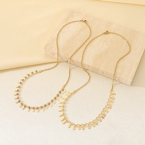 Detailed shot of golden teardrop pendant necklaces with colorful beads on stone texture