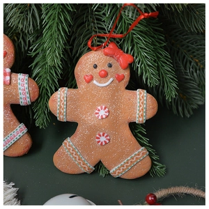Macro detail of gingerbread man Christmas ornament hanging on a green pine branch