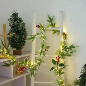 Detail view of snowy pine needle garland with red berries and warm LED lights