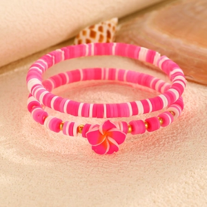 Dettaglio di braccialetti in perline Heishi rosa fatti a mano con ciondolo a frangipane