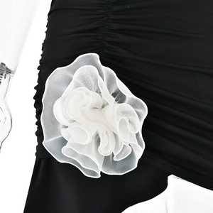 Detail eines eleganten weißen Netzblumen-Accessoires am schwarzen rückenfreien Kleid