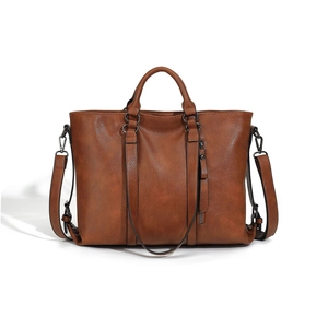 Detail view of large brown soft leather tote bag with vertical straps and side zip pocket