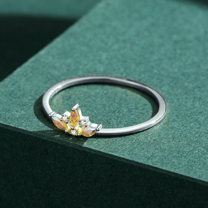 925 sterling silver crown ring with orange opal and zircon stones on green backdrop