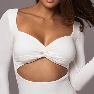 Détail d'un body blanc à manches longues avec nœud torsadé et découpe à la taille