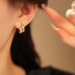 Gros plan sur des créoles géométriques en or avec émail blanc et détails en zircon