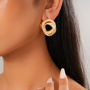 Close-up of golden geometric twisted knot hoop earrings on a female model