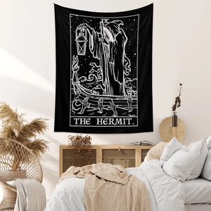 Detailed black and white The Hermit tarot tapestry hanging in a cozy bedroom